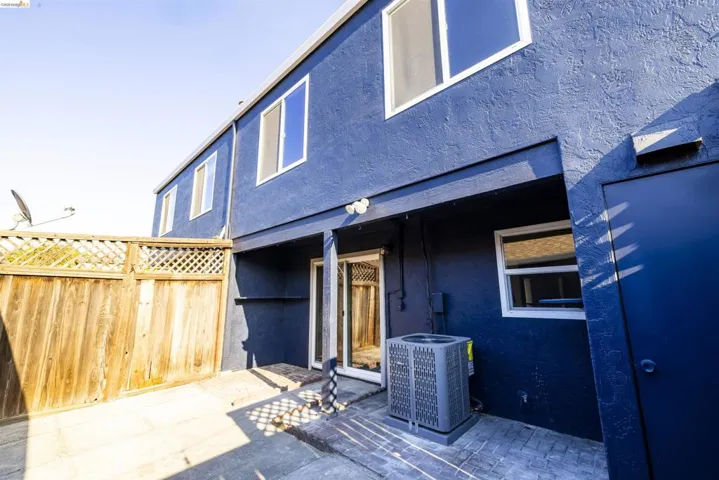 Rear exterior featuring a blue stucco finish and wood fencing