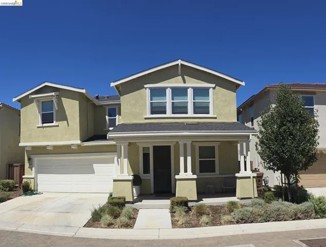 Two-story stucco exterior featuring a covered front porch, white garage door, concrete driveway, and front landscaping