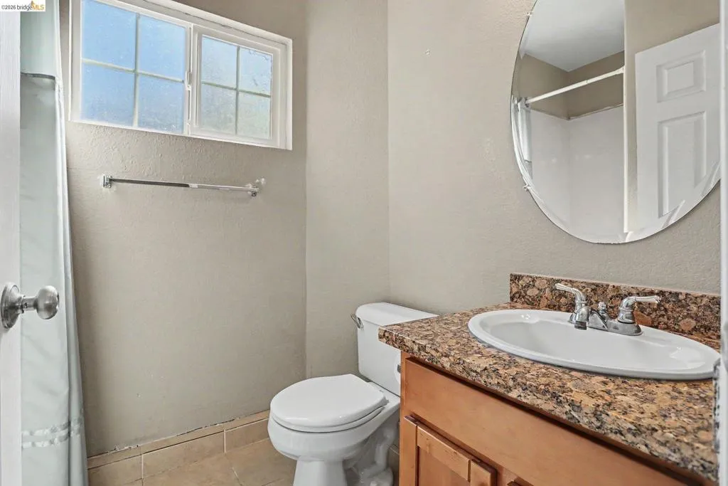 Bathroom featuring a vanity with a granular countertop and oval mirror