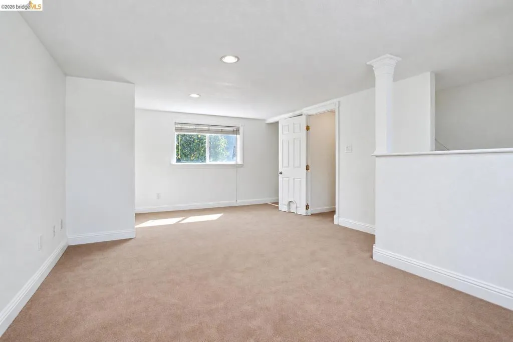 Carpeted room with recessed lighting and a single window