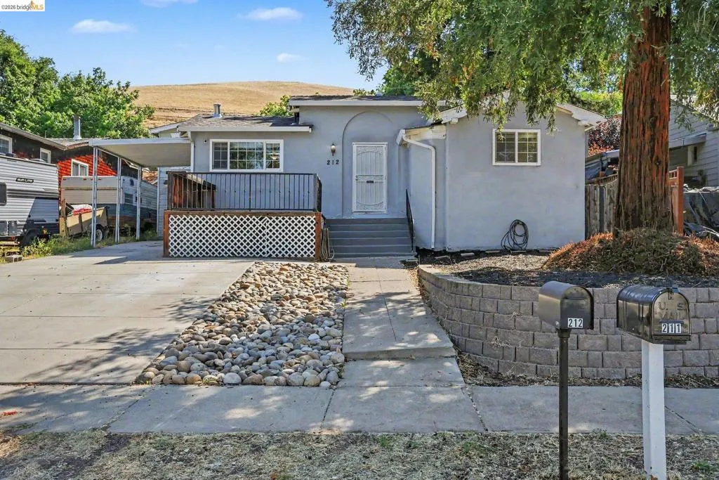 Stucco exterior home featuring an elevated front porch with lattice detailing