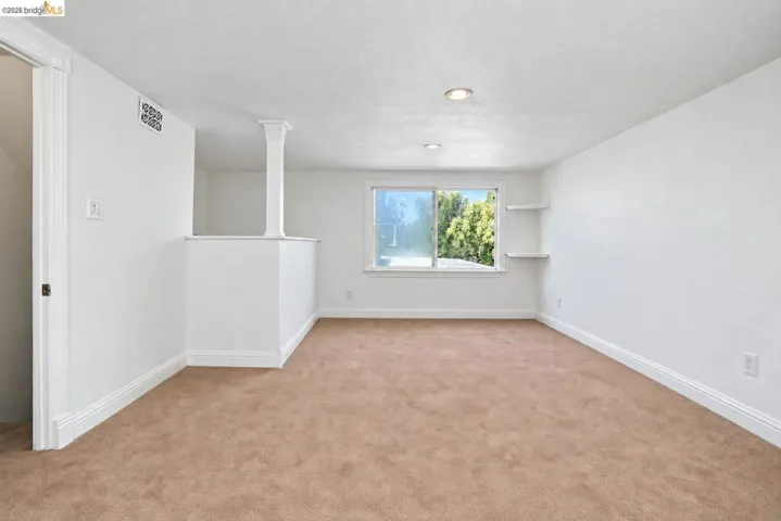 Neutral-toned carpeting, recessed ceiling lighting, and built-in shelving
