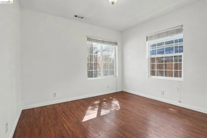 Room with rich wood-finish flooring and bright white walls