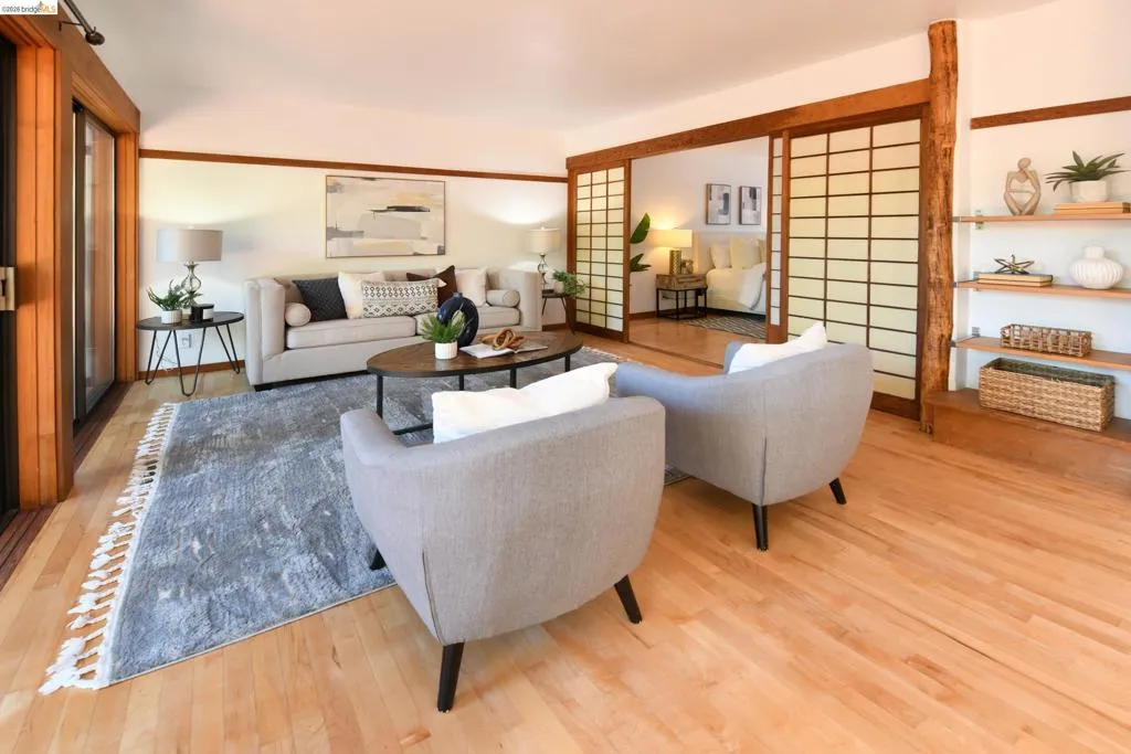 Living area featuring light wood-finish flooring, sliding shoji-style partition doors, built-in shelving, and a large sliding glass door with wood trim