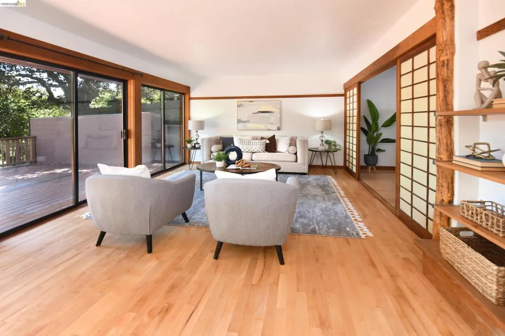 Bright living area featuring wood-finish flooring, a wall of sliding glass doors opening to a wood deck, and Shoji screen doors