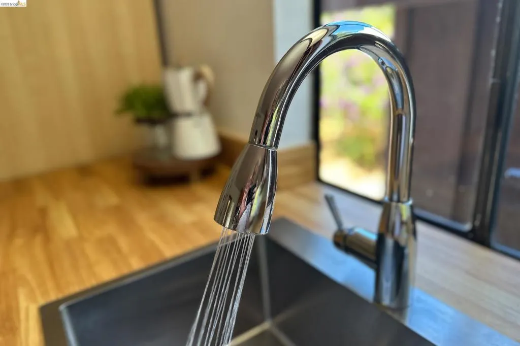 Stainless steel sink with a gooseneck pull-down faucet, set into wood-finish countertops
