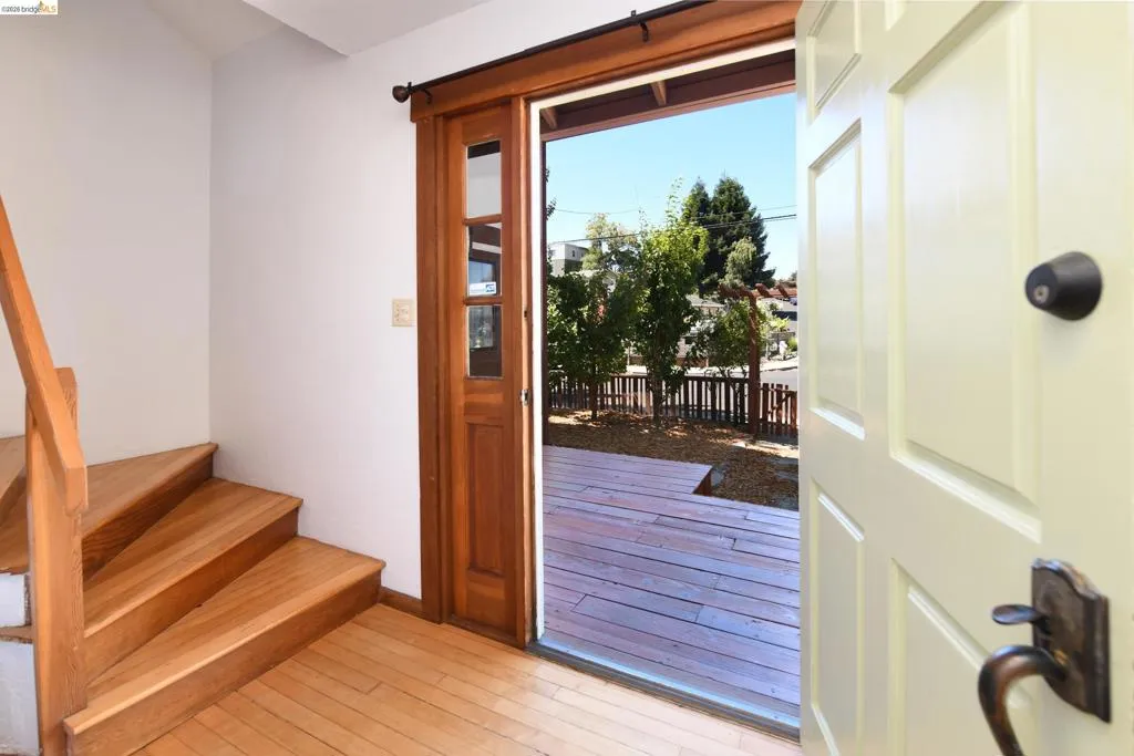 Inviting entry featuring wood-finish flooring, a wood staircase with a matching handrail, and a paneled entry door