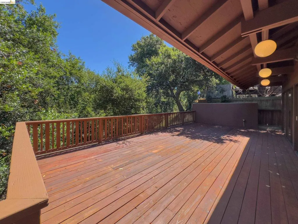 Expansive wood deck with a full-height railing, surrounded by mature trees
