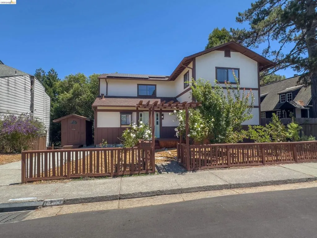Two-story residence featuring a brown and white exterior, a wood pergola entry, and a matching front fence