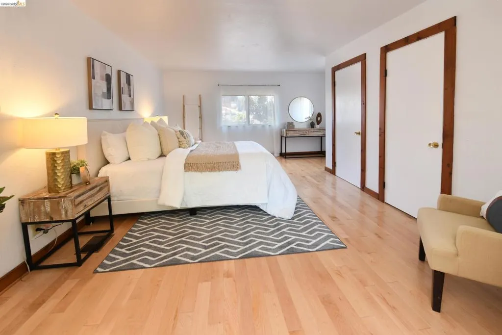 Light wood-finish flooring extending throughout, white walls, and bright window with natural light