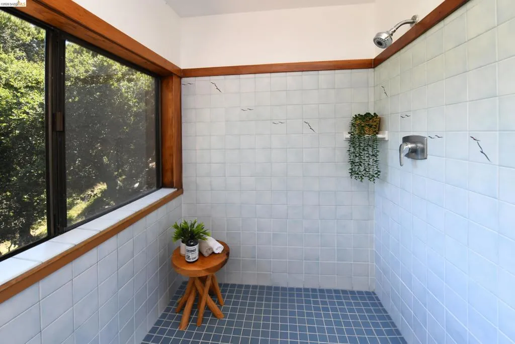 Tiled shower enclosure featuring light blue wall tiles with decorative accents and darker blue floor tiles