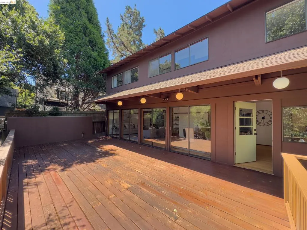 Expansive wood deck with a brown finish, featuring a full-length railing and a solid privacy wall