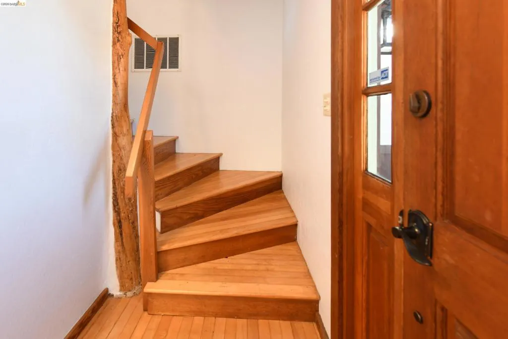 Curved staircase featuring wood-finish treads and risers, a natural wood newel post, and a matching wood-finish handrail