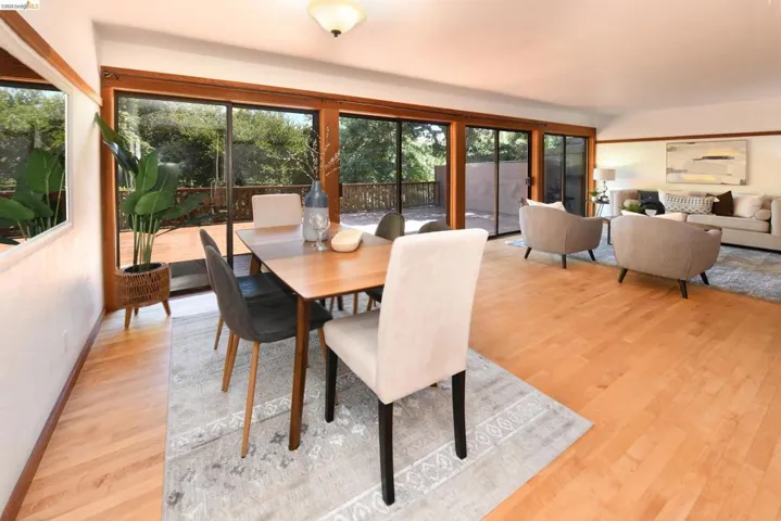 Open-concept living space featuring wood-finish flooring, a contemporary ceiling light fixture, and multiple glass sliding doors providing abundant natural light and exterior access to a wooden deck