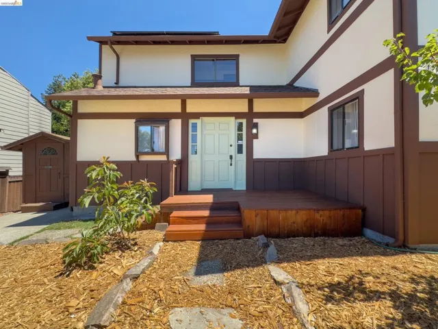 Front exterior featuring a light-toned entry door, an expansive wooden deck, and a distinct brown and cream facade