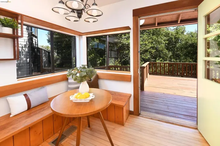 Breakfast nook featuring built-in wooden bench seating with integrated storage, wood-finish flooring, a contemporary chandelier, and multiple windows