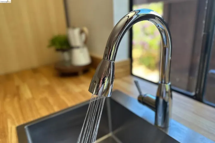 Stainless steel sink with a gooseneck pull-down faucet, set into wood-finish countertops