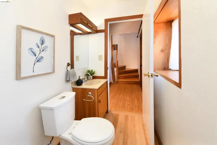 Compact bathroom featuring a white toilet, wood-finish vanity with an integrated sink, and an illuminated medicine cabinet