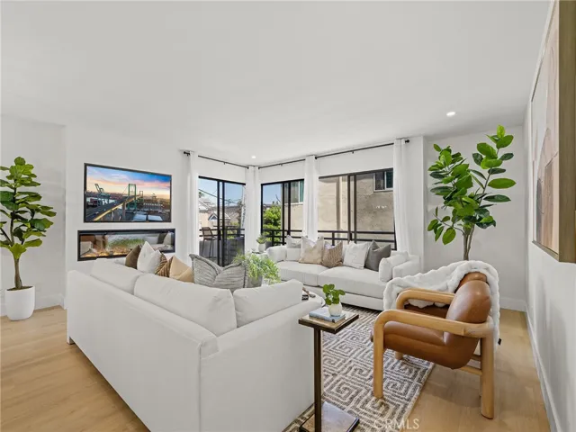 A view to the fireplace with mounted and staged tv. Framed by the three slider doors providing that generous ocean air flow.