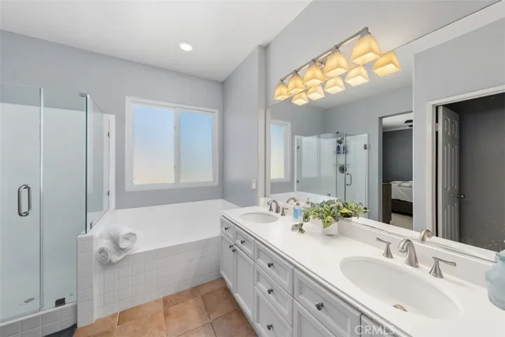 Primary bathroom with dual sinks, frameless glass shower enclosure, and soaking tub