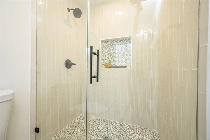Downstairs primary bathroom with walk in shower with custom tile work