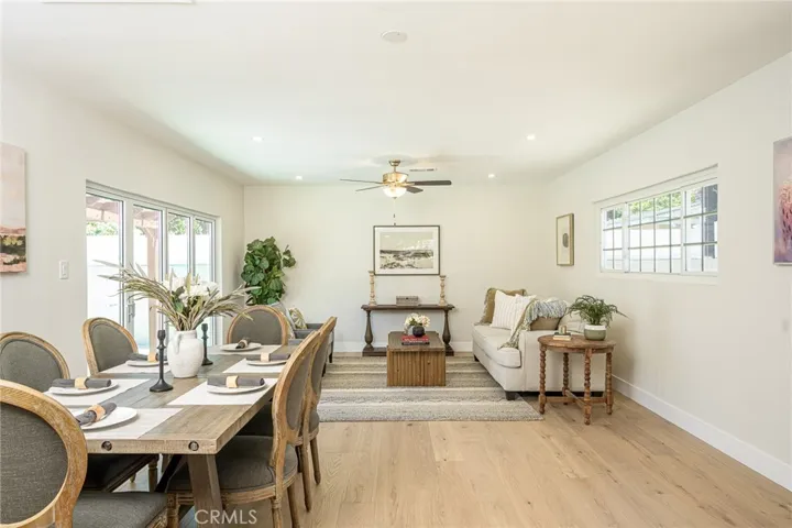 Back dining and living area with wide plank flooring and new ceiling fan.