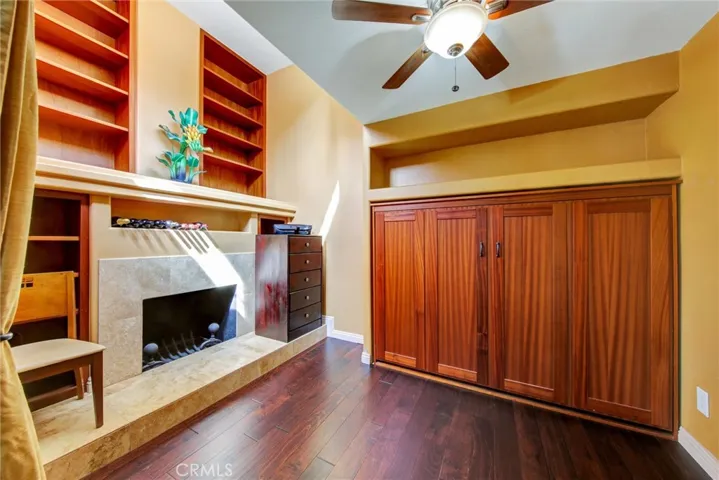 Second bedroom with fireplace, built-in bookcases and matching custom African mahogany wood Murphy bed.