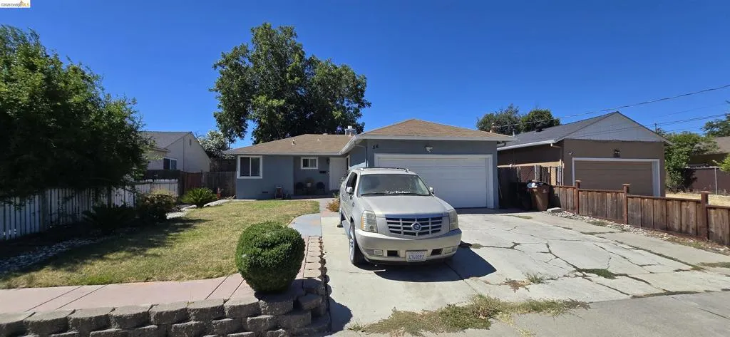 Single-story residence featuring a two-car garage, light gray exterior siding, and a paved driveway