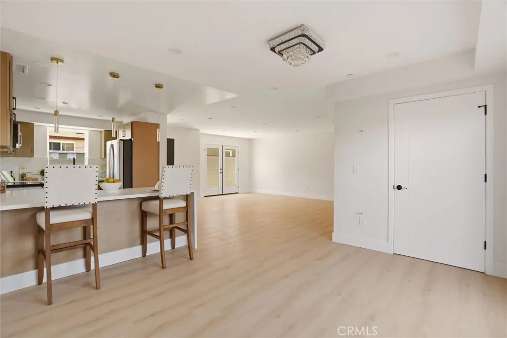 Unstaged living space and kitchen area, and dining area  from unit B, showing waterfall counter top
