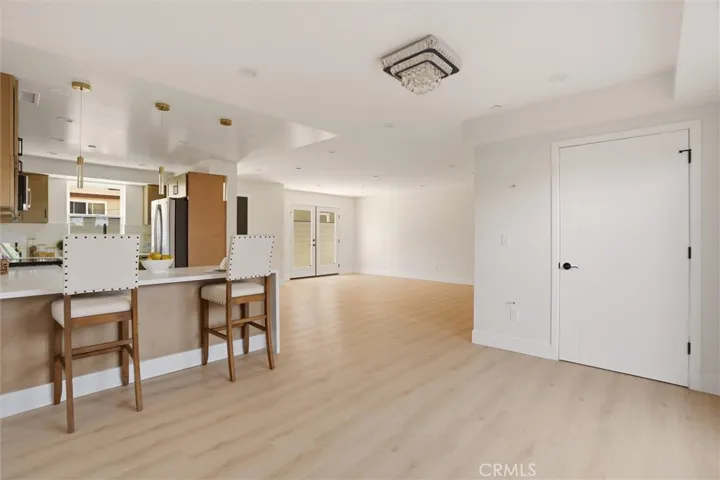 Unstaged living space and kitchen area, and dining area  from unit B, showing waterfall counter top