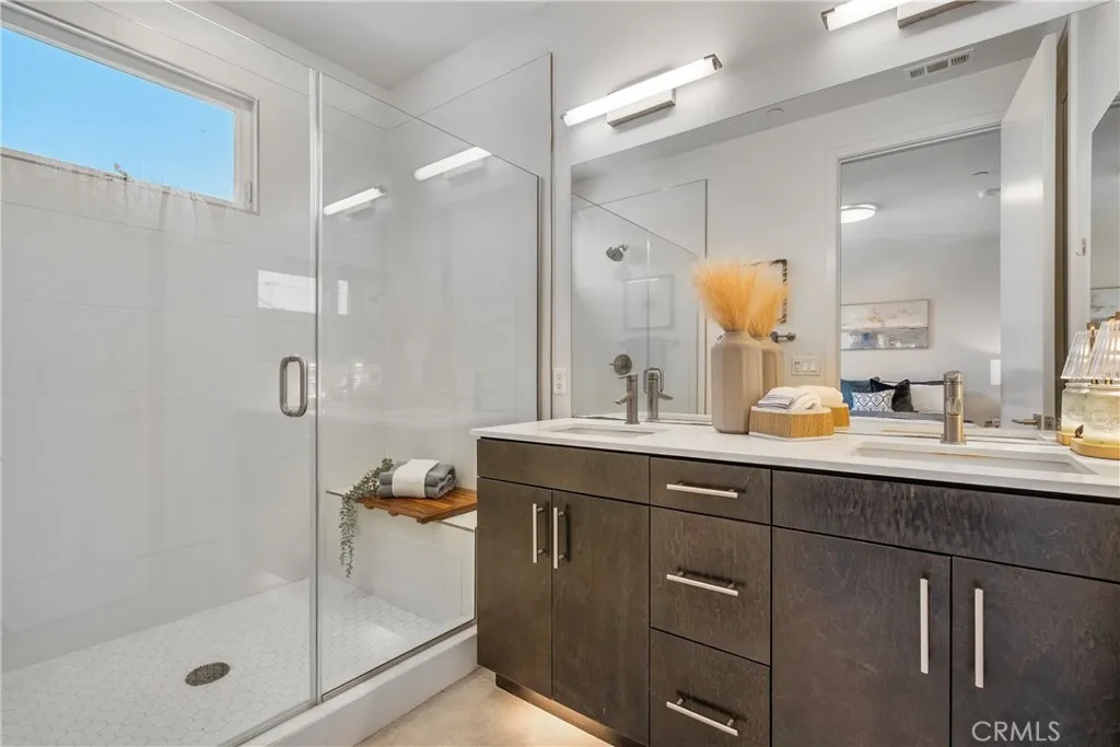 Primary suite bathroom with shower seat and double sink