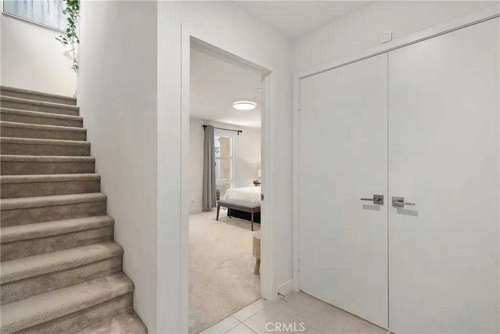 Main entrance stairway with view of guest suite on first level & double door to walk in mud room/storage closet