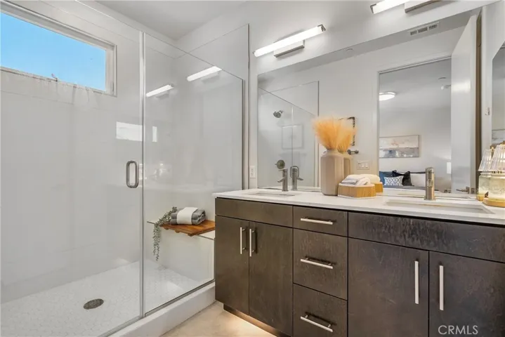 Primary suite bathroom with shower seat and double sink