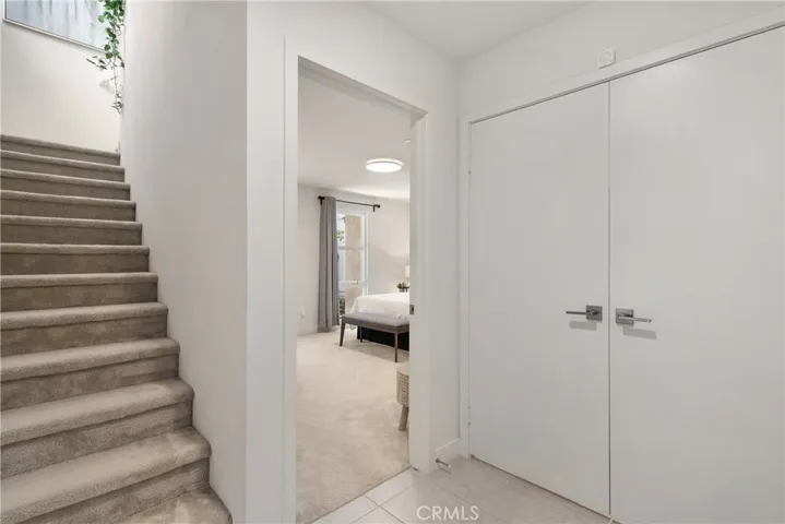 Main entrance stairway with view of guest suite on first level & double door to walk in mud room/storage closet