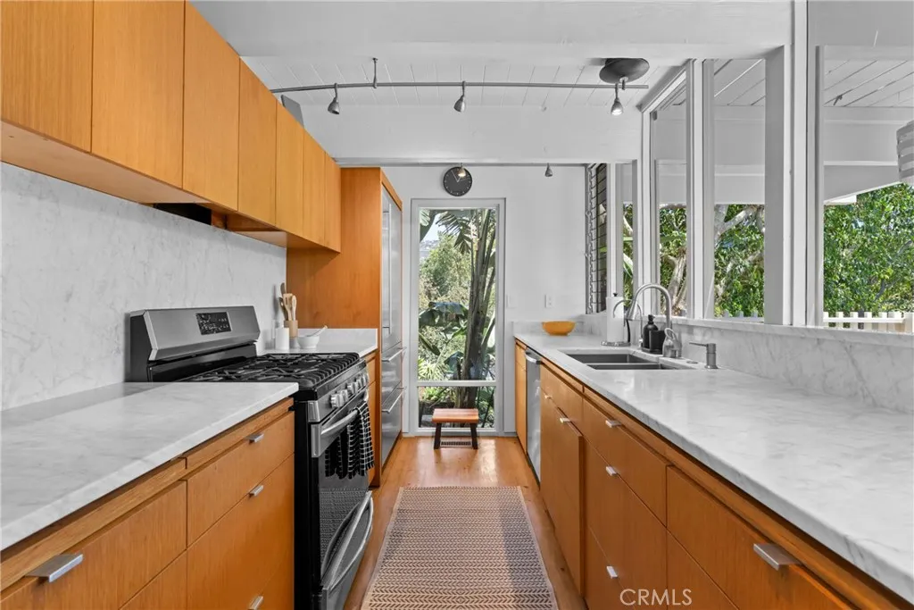 kitchen with quartz counter tops, gas stove, dishwasher, disposal, and refrigerator