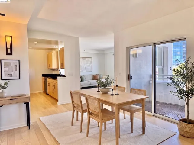 Dining area featuring wood-finish flooring, a sliding glass door to a private balcony, and an open layout connecting to the living space and kitchen