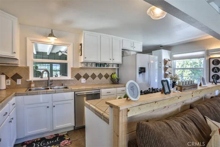 Kitchen has a gas stove, dishwasher, tile counters and floors