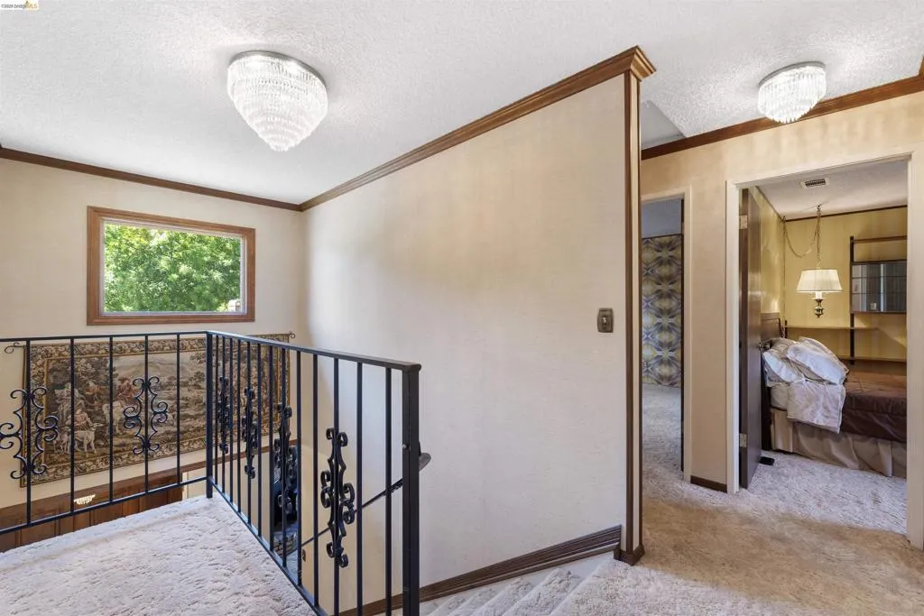 Stairwell featuring wrought iron railing with ornate details, a framed window, and carpeted flooring