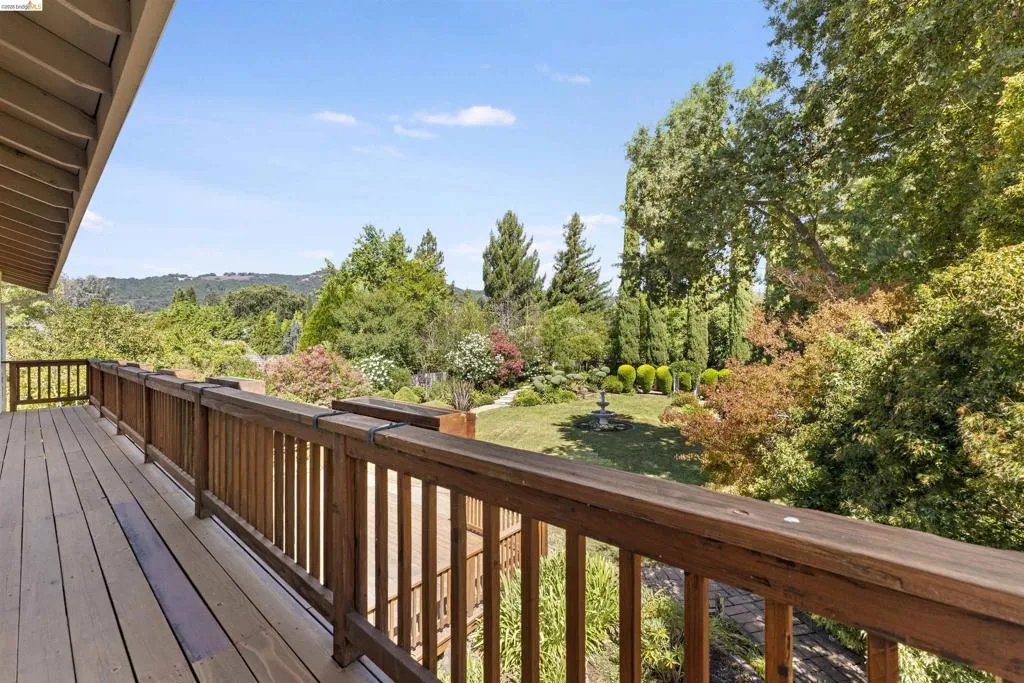 Spacious wood-finish deck overlooking a verdant backyard with mature trees and landscaped shrubbery