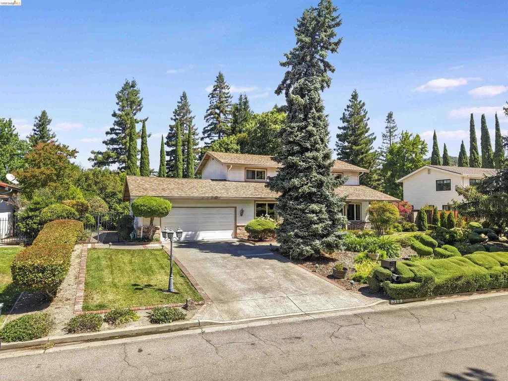 Two-story residence featuring a two-car garage, concrete driveway, and mature landscaping
