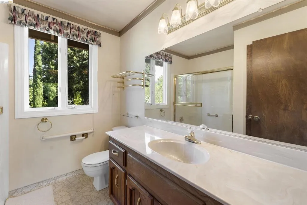 Bathroom vanity featuring a single-basin sink with an integrated countertop, wood-finish cabinetry, and an expansive wall-mounted mirror