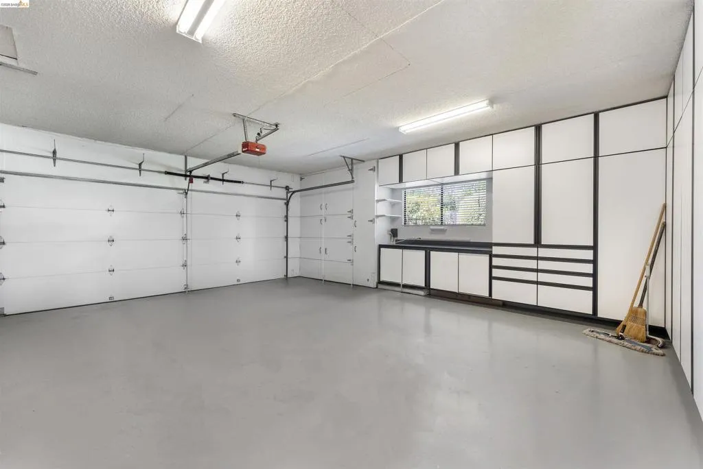 Spacious garage featuring two overhead doors, built-in cabinetry, a window, and fluorescent lighting