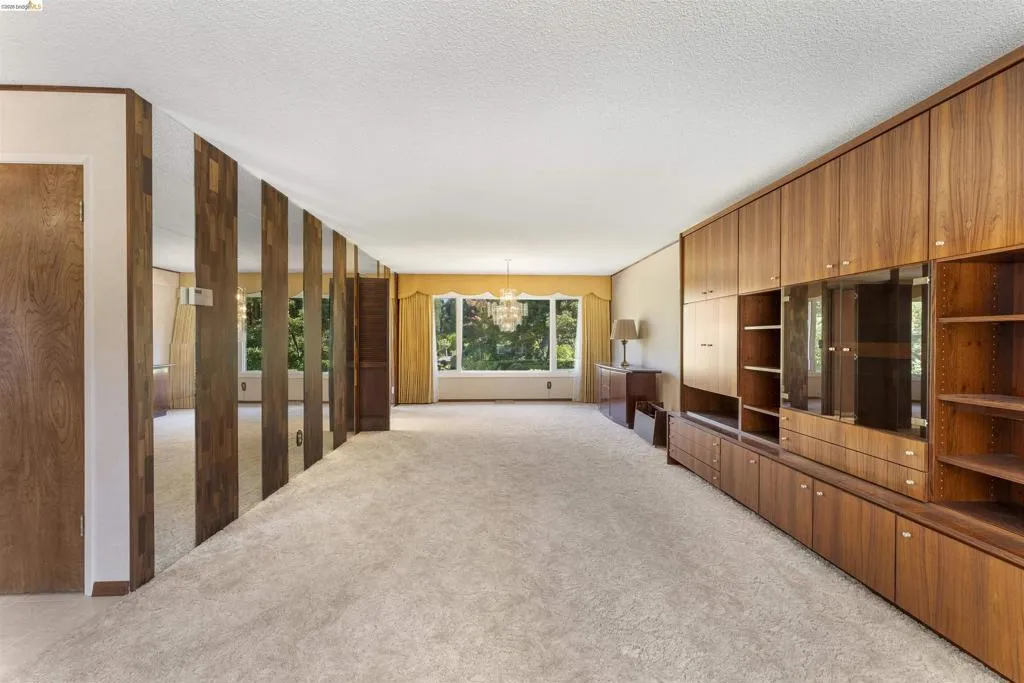 Spacious room featuring extensive built-in wood cabinetry, integrated shelving, and mirrored accents