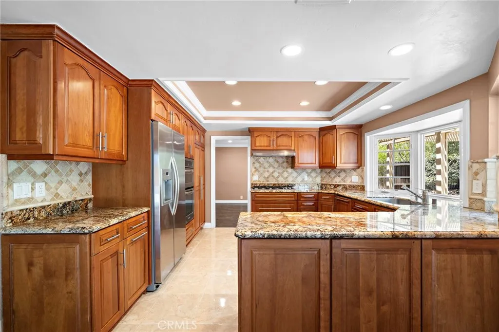 Remodeled kitchen is conveniently located with high-quality appliances including a KitchenAid fridge, oven, and microwave, a Dacor cooktop, and a Bosch dishwasher.