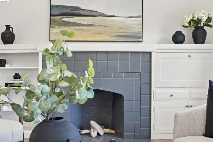 Tiled fireplace with a hearth and mantel, flanked by built-in shelving and cabinetry with brass hardware
