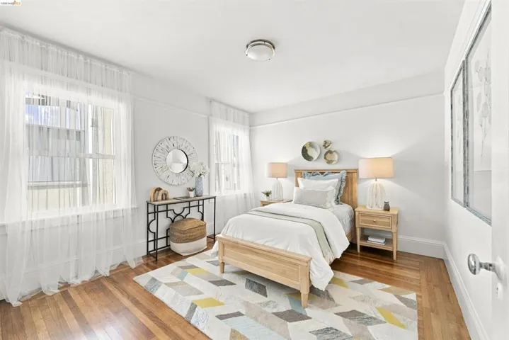Bright room featuring two windows, wood-finish flooring, and white walls
