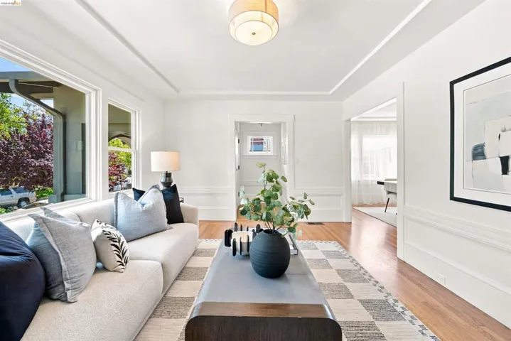 Sunlit interior featuring wood-finish flooring, white walls, and decorative ceiling trim