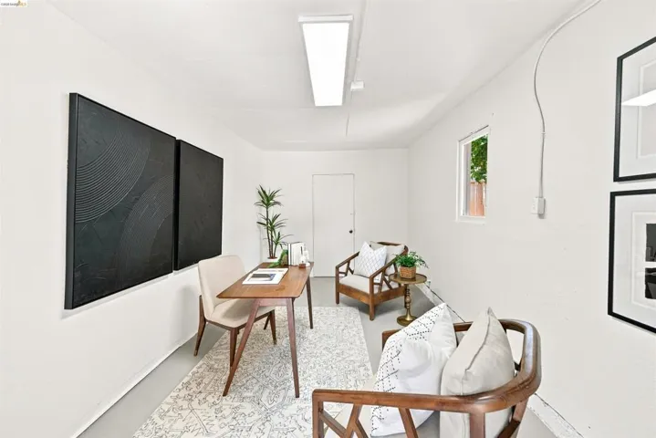 Versatile interior space featuring white painted walls and flooring, a white door, and a single window allowing natural light