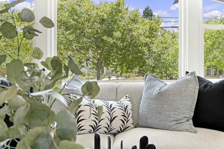 Bay window with white trim, featuring a light-colored sofa with throw pillows