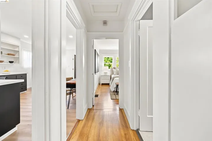Hallway featuring wood-finish flooring, white walls, and bright overhead lighting